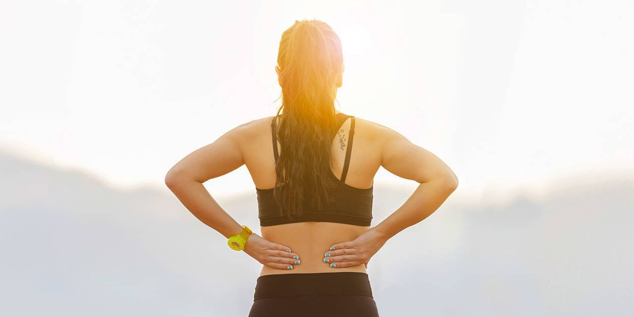 Woman in sportswear facing into sunrise