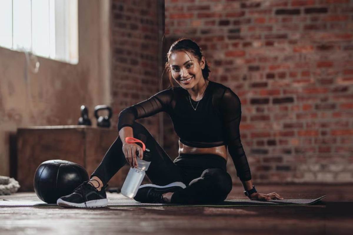 Woman sat in gym next to kettle bell and water bottle