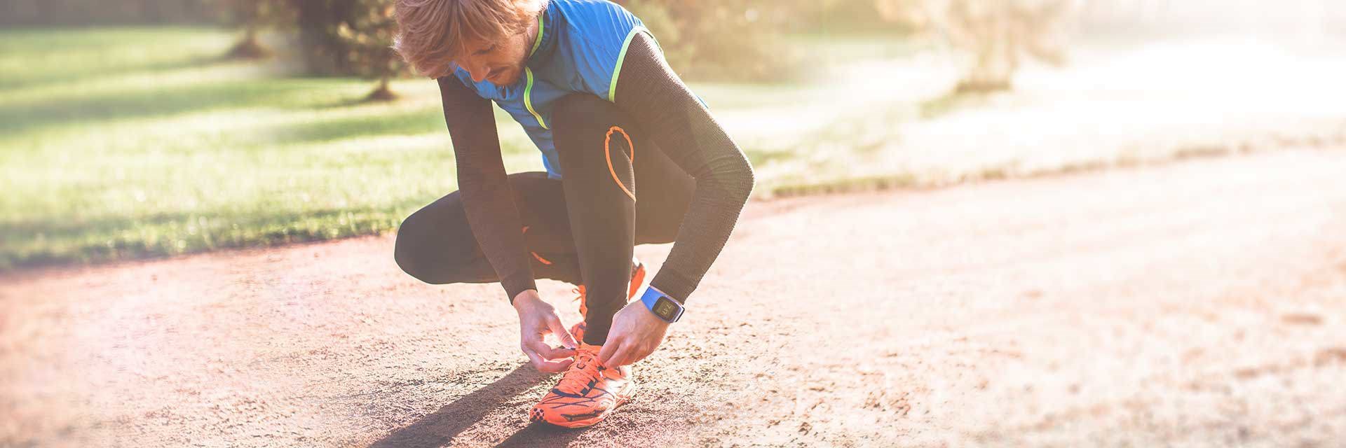 Man knelt down tying shoelace