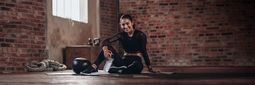 Woman sitting in the gym with water bottle